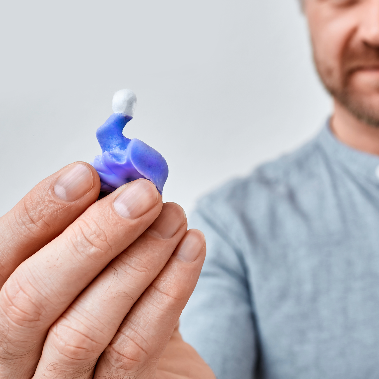 En mann som holder en øreavstøpning som brukes til formstøpte ørepropper